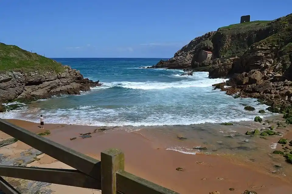 Playa de Santa Justa con su ermita incrustada en el acantilado en Ubiarco, rincón imprescindible que ver en Santillana del Mar.