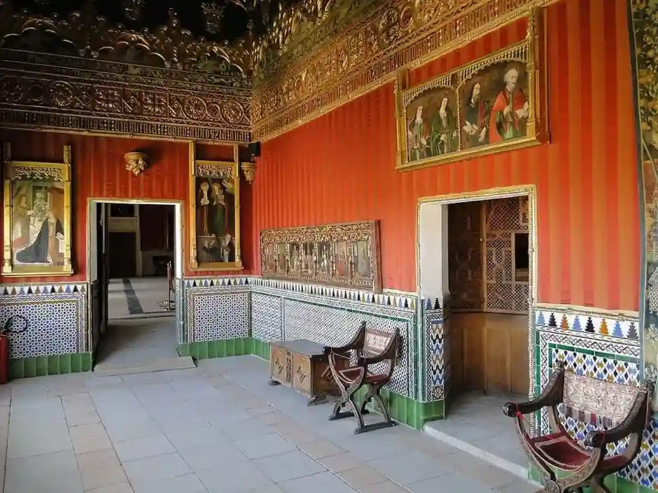 El Alcázar de Segovia por dentro: interior de la Sala del Cordón con paredes enteladas en rojo, friso dorado y zócalos de azulejos mudéjares.