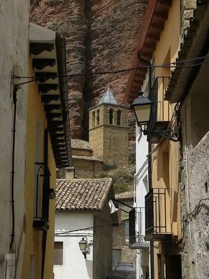 Qué ver en Riglos: torre de la iglesia de Nuestra Señora del Mallo entre las calles del pueblo con la roca de los Mallos al fondo