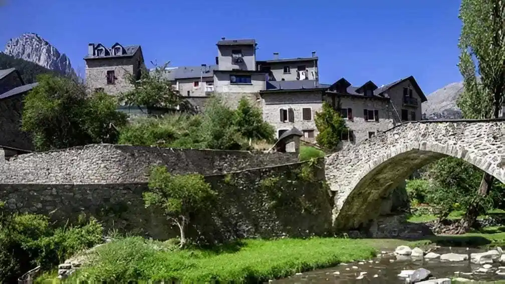 Puente de piedra medieval sobre el río y casas de arquitectura tradicional, una de las mejores cosas que ver en Sallent de Gállego.