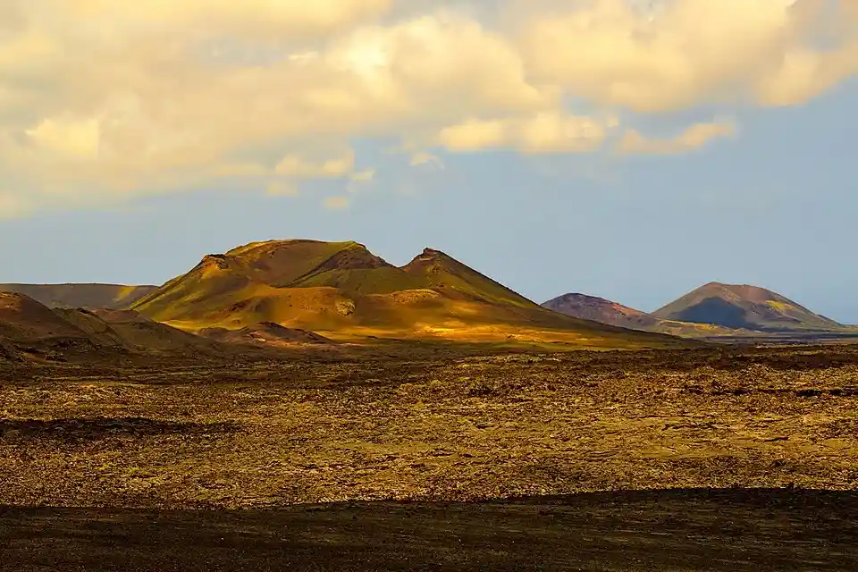 Conos volcánicos y campos de lava iluminados por el atardecer en el Parque Nacional de Timanfaya, Lanzarote.