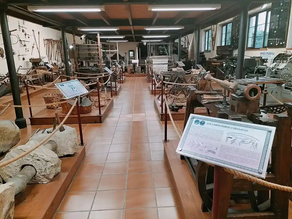 Sala de oficios tradicionales del Museo Etnográfico Juan Pérez Villamil en Puerto de Vega, con herramientas de carpintería, telar e imprenta.