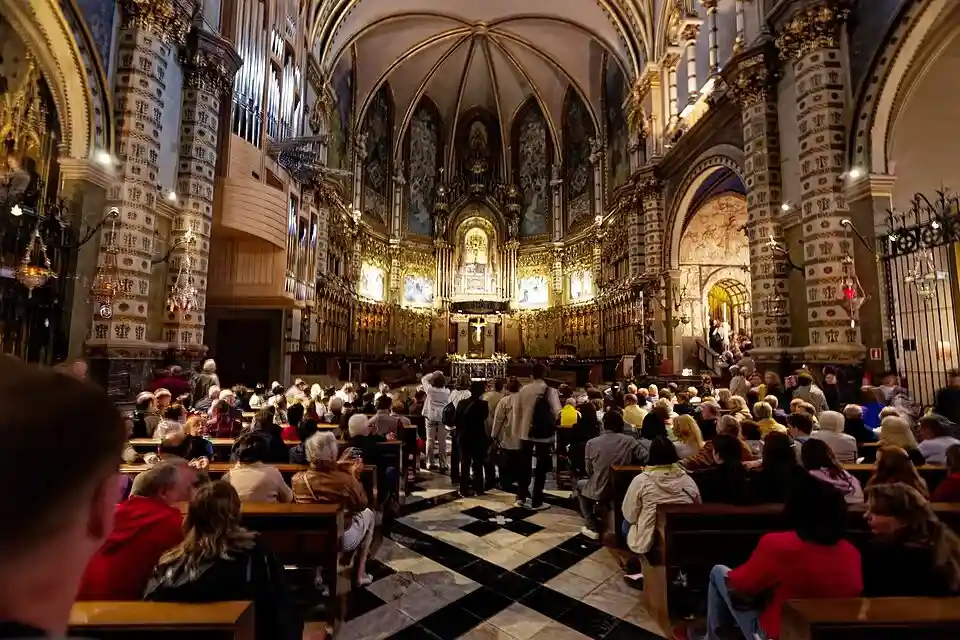 Interior de la basílica del monasterio con fieles sentados frente al altar mayor en el Macizo de Montserrat.