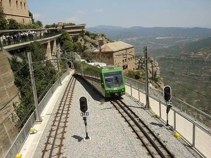 Tren cremallera verde de FGC circulando por las vías de montaña en el Macizo de Montserrat.