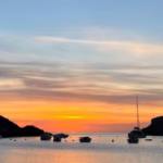 Atardecer en Ibiza: Vista espectacular del sol poniéndose sobre el mar Mediterráneo en San Antonio, con tonos dorados y rosados en el cielo.