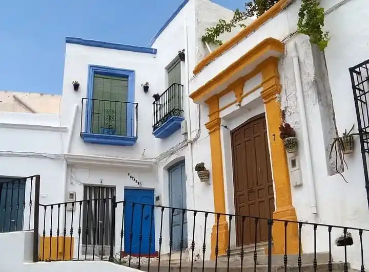 Fachadas de casas tradicionales blancas con marcos en azul y amarillo en una calle típica de Níjar, Almería