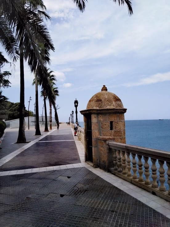 Garita de vigilancia histórica en el Paseo de la Alameda Apodaca de Cádiz, con palmeras y vista al océano Atlántico