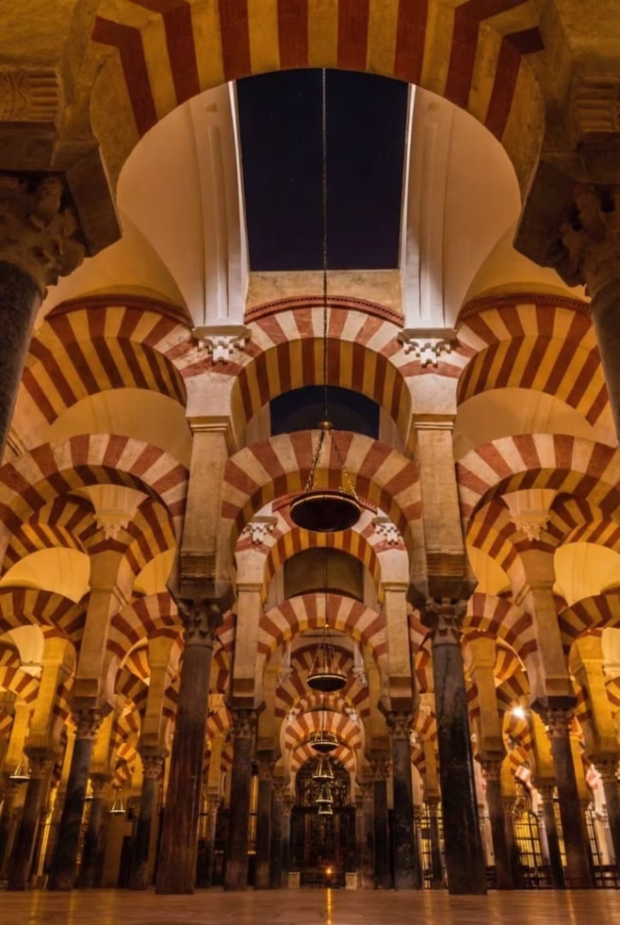 Interior de la Mezquita-Catedral de Córdoba con sus arcos bicolores iluminados, uno de los sitios de Andalucía que visitar al menos una vez en la vida