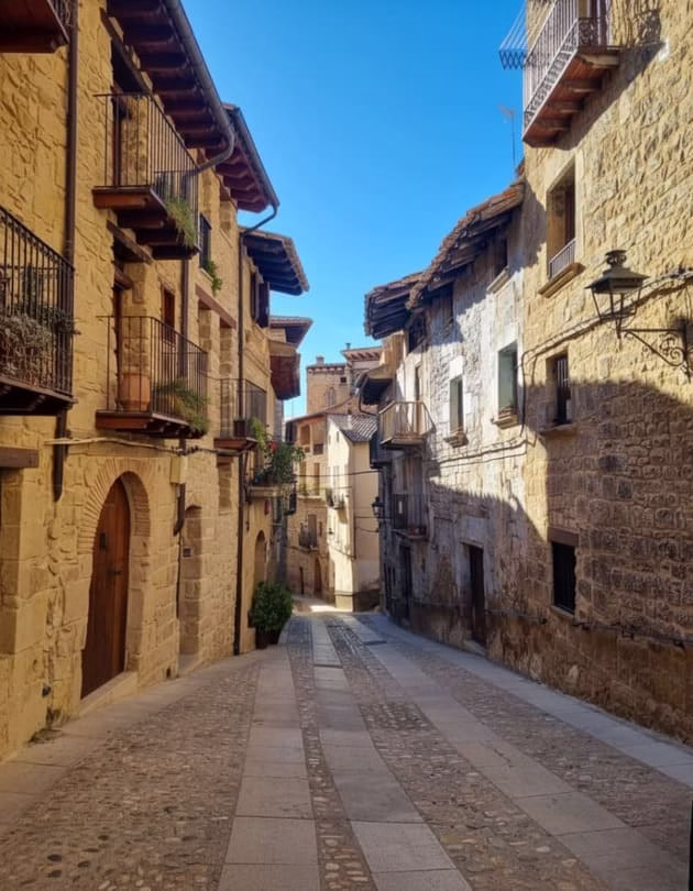 Arquitectura de piedra en una calle de pueblo soleada, ideal para turismo rural.