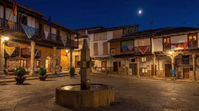 plaza de Valverde de la Vera iluminada de noche, con casas de arquitectura verata, uno de los pueblos más bonitos de la comarca de la Vera