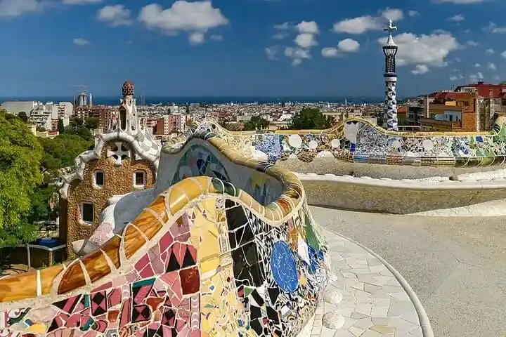 Banco ondulado de mosaico trencadís en el Park Güell con vistas panorámicas de la ciudad de Barcelona y el mar Mediterráneo.