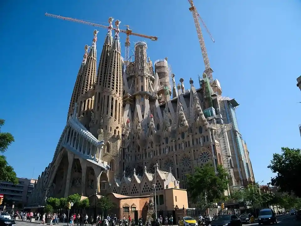 Vista exterior de la Sagrada Familia y la Fachada de la Pasión con las torres en construcción bajo el cielo azul de Barcelona.