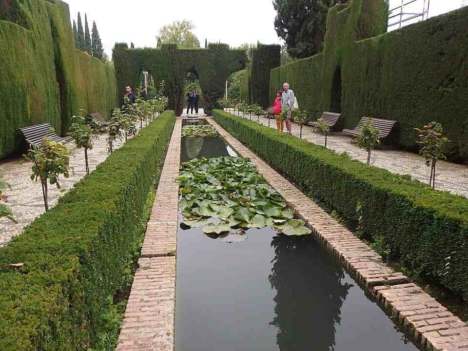 Estanque central con nenúfares y arcos de ciprés en los Jardines Bajos del Generalife, Granada.